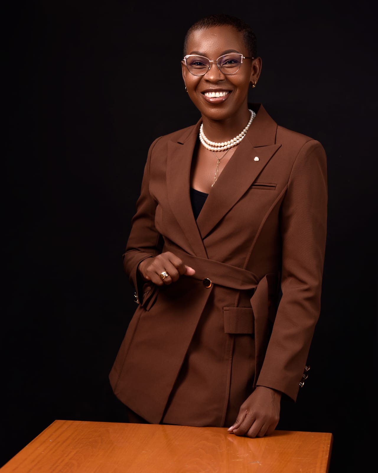 Eunice Ireri in a brown suit, standing