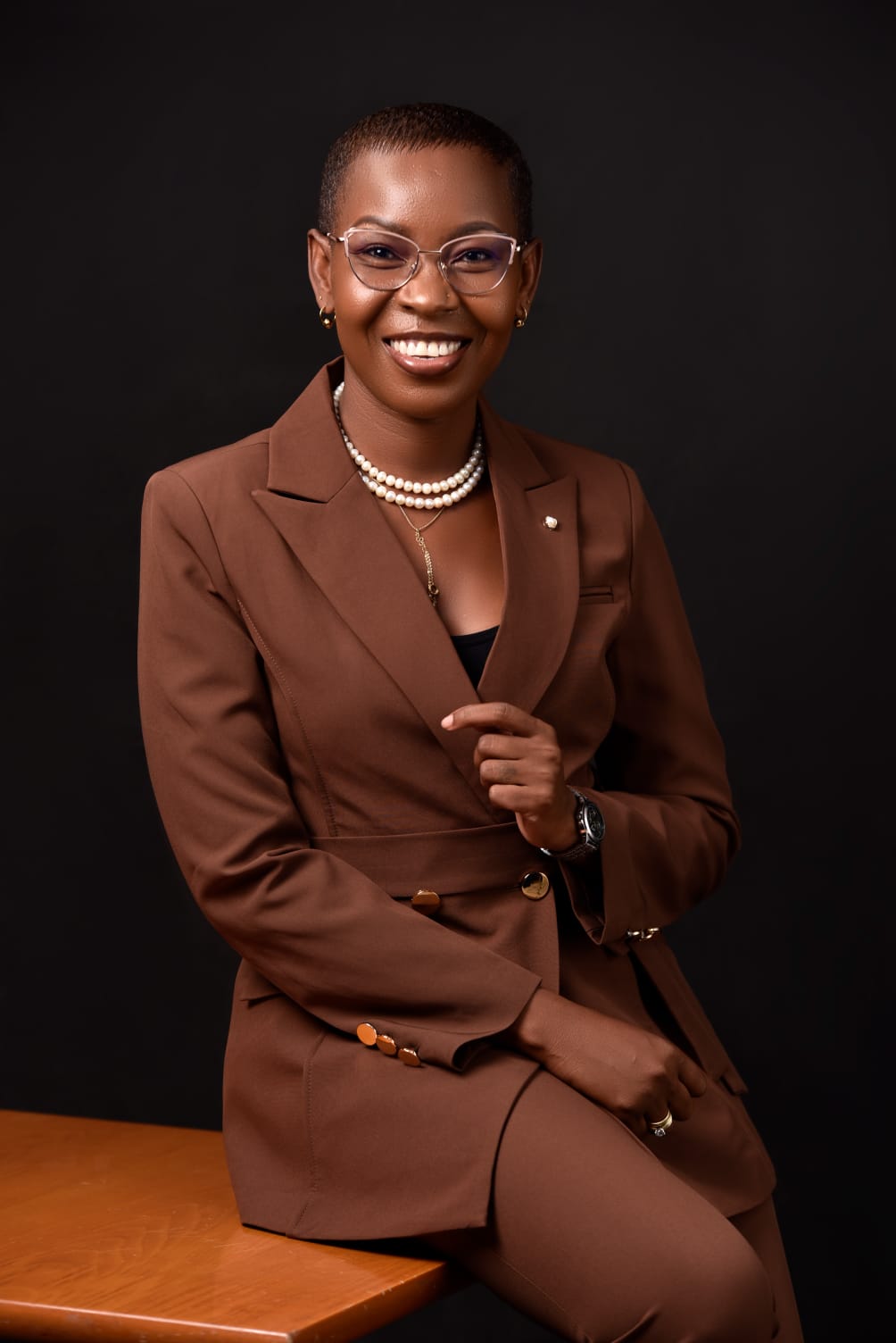 Eunice Ireri seated at a desk in a brown suit