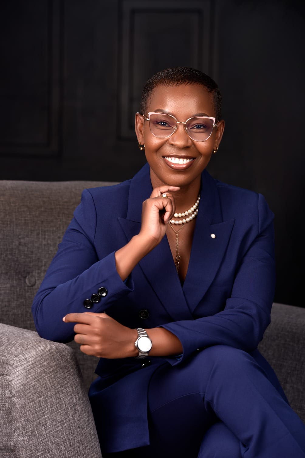 Eunice Ireri in a lilac suit, standing in a book-lined study